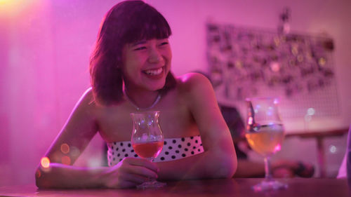Portrait of a smiling young woman in drinking glass