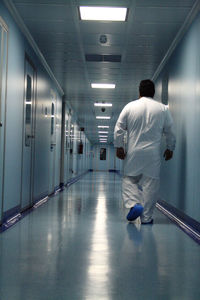 Rear view of man walking in illuminated corridor