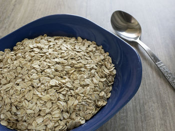 Close-up of oat flakes in bowl on wooden table