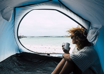 Woman looking at sea while sitting in tent