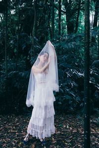 Woman standing on field against trees in forest