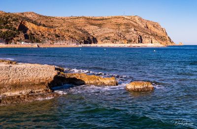 Scenic view of rocks in sea against clear sky