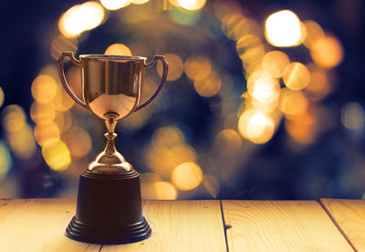 Close-up of golden trophy on wooden table against defocused background