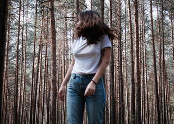 Woman standing against tree trunk in forest