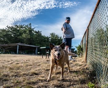 Mid adult man with dog standing on grassy field at park