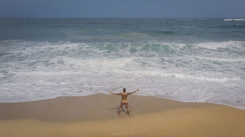 Rear view of man at beach against sky