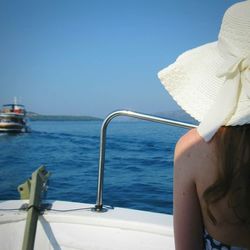 Midsection of woman by sea against clear sky