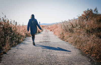 Rear view of man walking on footpath