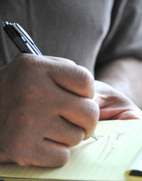 Man writing notes on paper outside.