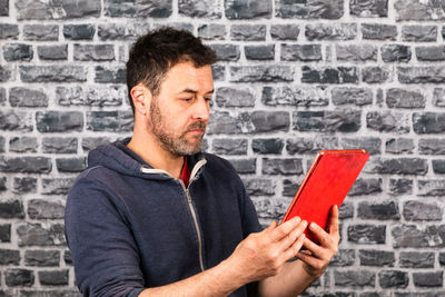 Midsection of man holding camera against wall