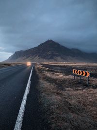 Road sign by mountain against sky