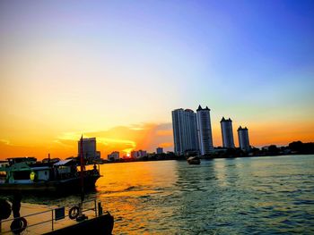 Scenic view of river and buildings against sky during sunset