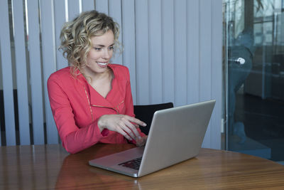 Mid adult woman using mobile phone while sitting on table