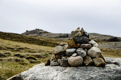 Stack of stones on rock against sky