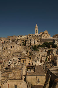 View at old buildings, walls, roofs and rock with religious cross in ancient town, sassi de 