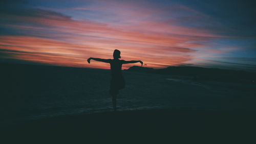 Rear view of man standing on mountain against sky during sunset