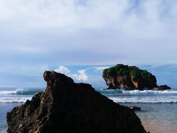 Rock formation on beach against sky