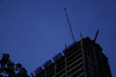 Low angle view of construction site against clear blue sky