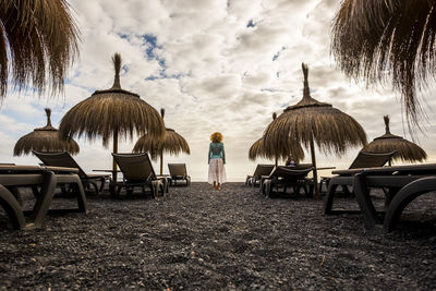 Woman standing amidst thatched roof at beach