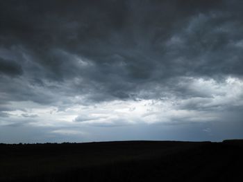 Silhouette landscape against cloudy sky