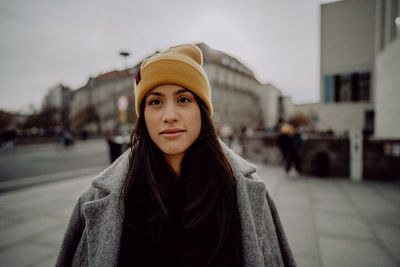 Portrait of woman wearing knit hat standing in city
