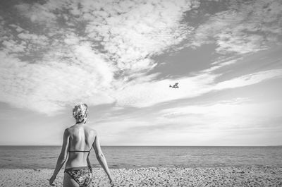 Rear view of woman on beach against sky
