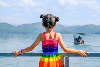 Rear view of girl wearing colorful dress while looking at lake