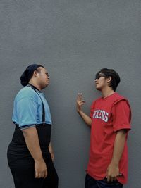Side view of young couple standing against wall