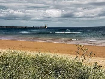 Scenic view of beach against cloudy sky