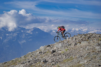 Man riding bicycle on mountain against sky