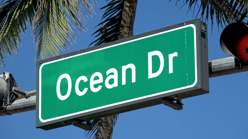 Low angle view of road sign against blue sky