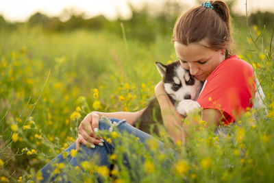 Side view of young woman with dog on field