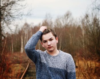 Portrait of young woman standing against blurred background