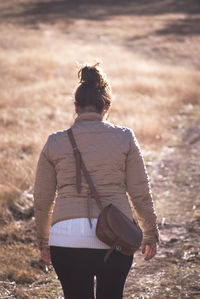 Rear view of woman walking on field