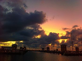 Silhouette of city against cloudy sky at sunset