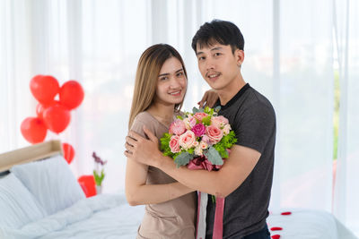 Portrait of couple kissing on flower against white wall