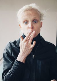 Portrait of mid adult man smoking against gray background