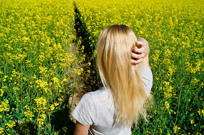 High angle view of young woman with hand in hair on field