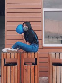 Woman sitting on wooden wall