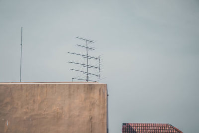 Low angle view of telephone pole by building against sky