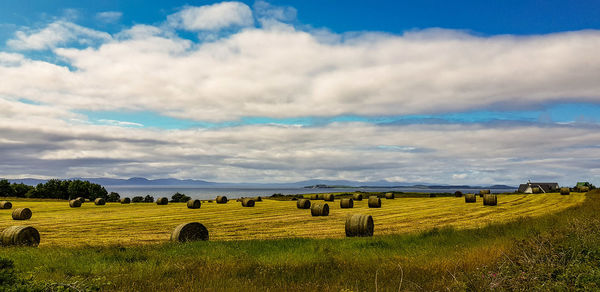 Hay bales on field against sky