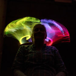 Close-up of woman with arms raised against black background