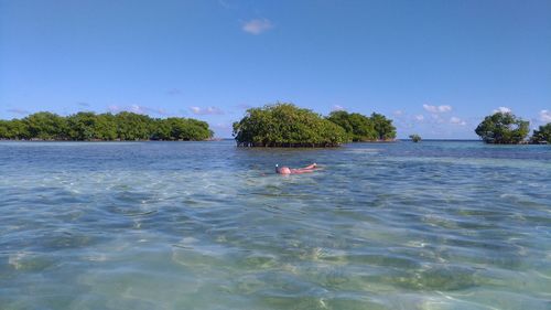 Man swimming in sea against blue sky