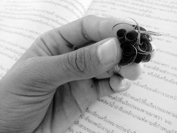 Cropped hand holding pencil shavings on book