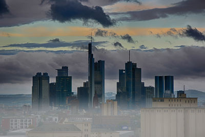 Digital composite image of modern buildings against sky during sunset