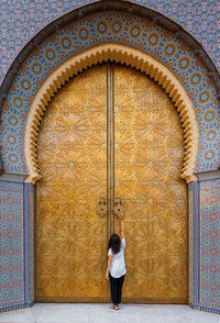 Rear view of woman standing against door of building