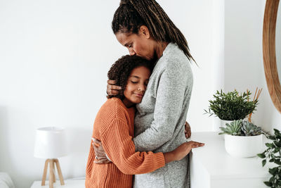 Mature woman embracing daughter at home