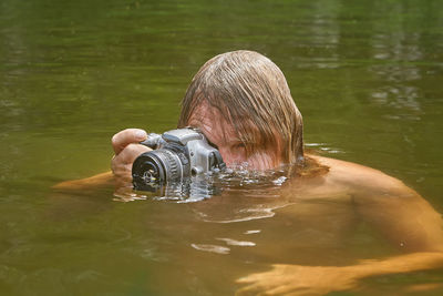 Portrait of man photographing swimming in lake