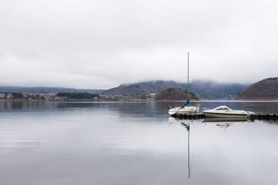 Sailboats moored on lake against sky