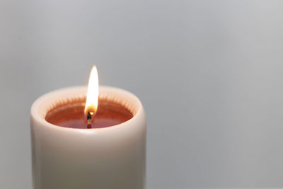 Close-up of illuminated candle against white background